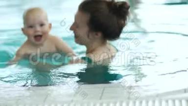 婴儿和他妈妈在室内游泳池游泳。 孩子对这个过程很高兴，也很有激情，妈妈`天